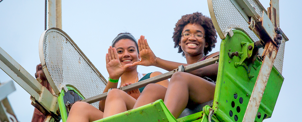 Students riding a Ferris wheel and throwing up the U